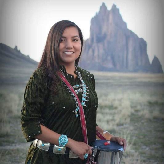 Talibah Begay in traditional navajo regalia, holding a drum for navajo song and dance.