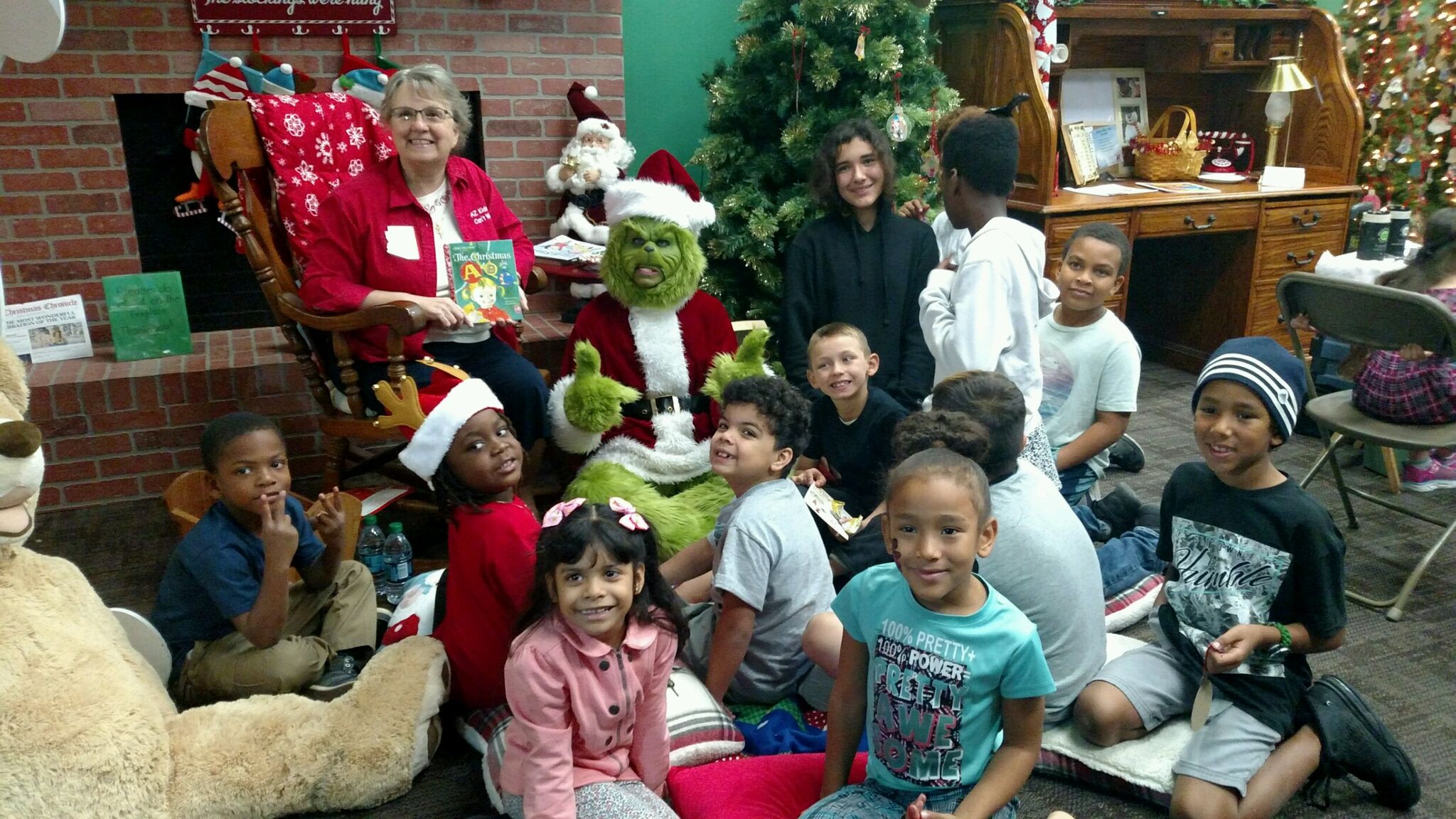 Arizona Superintendent of Public Instruction and costumed Grinch with kids in front of a Christmas tree.