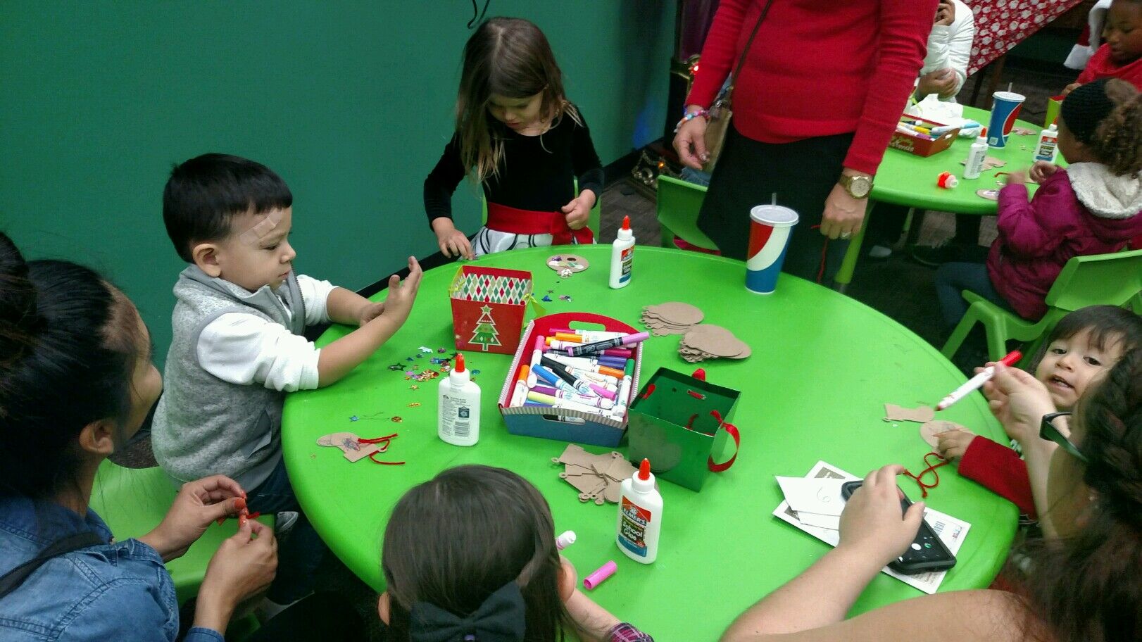 Children at a green table making Christmas ornaments.