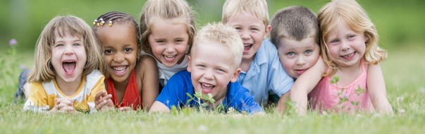 seven children laying the grass smiling