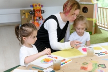 preschool teacher teaching art painting with water colors